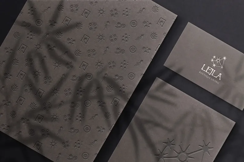 The Lejla icons embossed into dark textured paper under leaf shadows